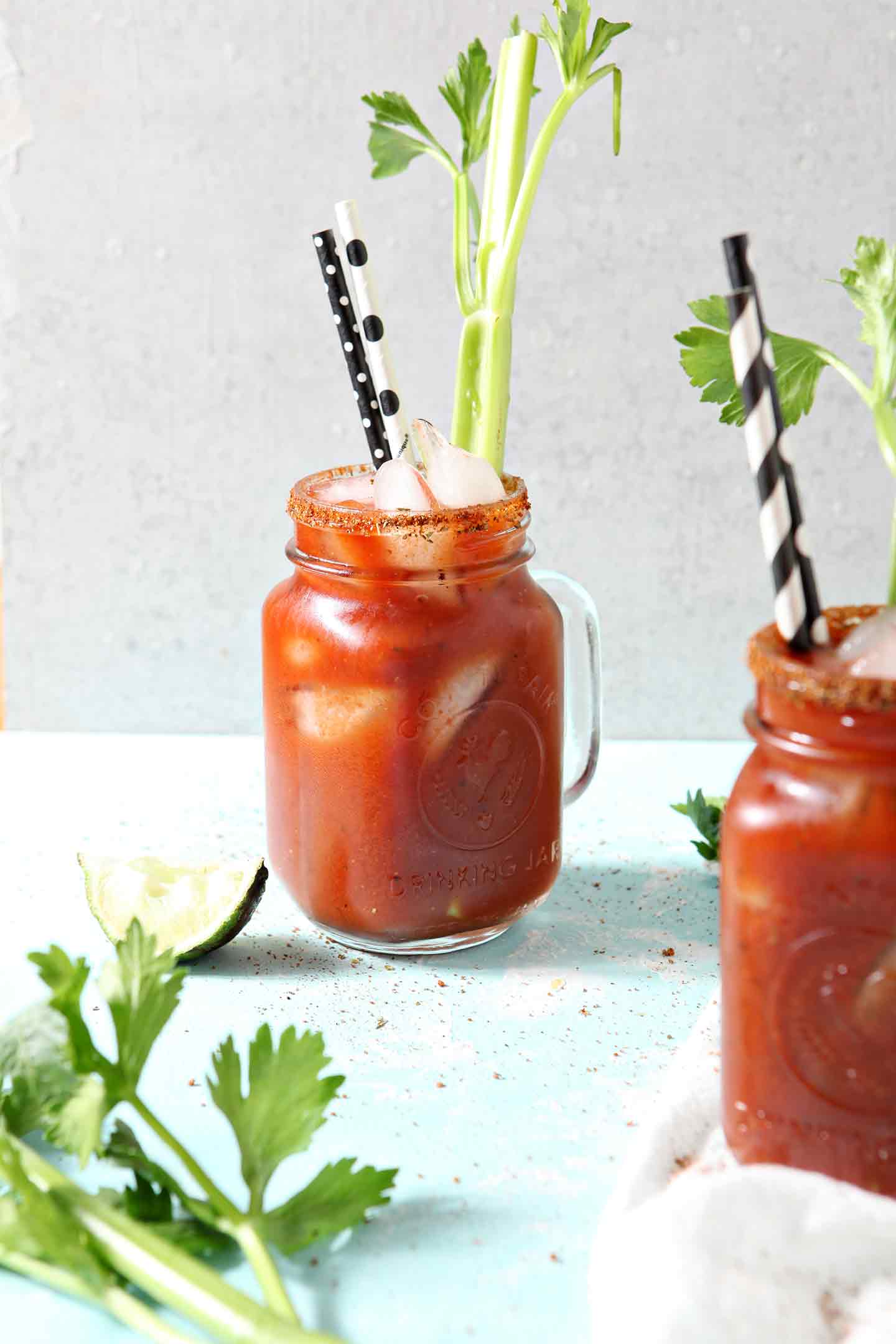 Two BBQ Bloody Marys stand next to each other on a turquoise background