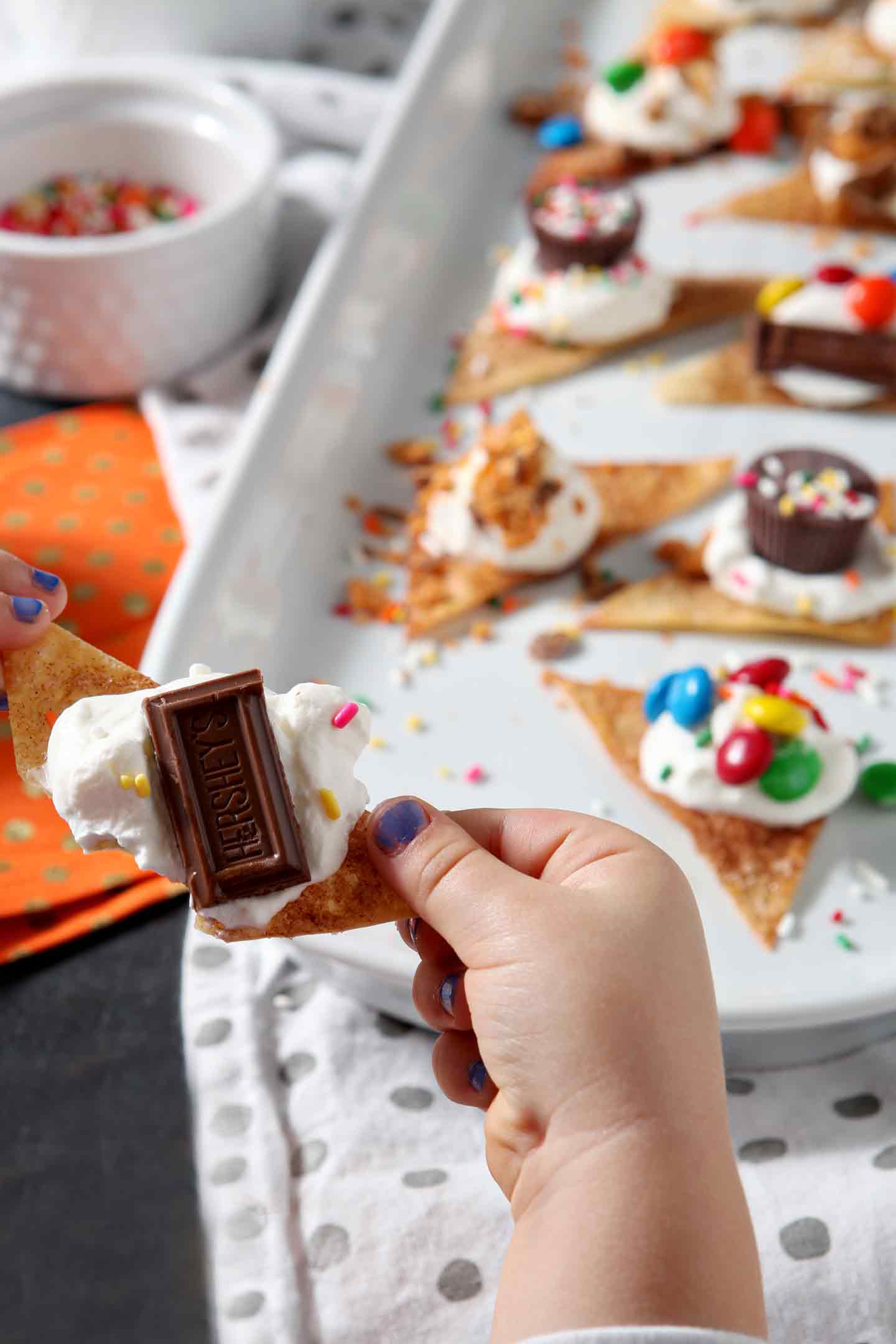 A girl holds a Halloween Dessert Nacho with the platter of the individually made nachos in the background