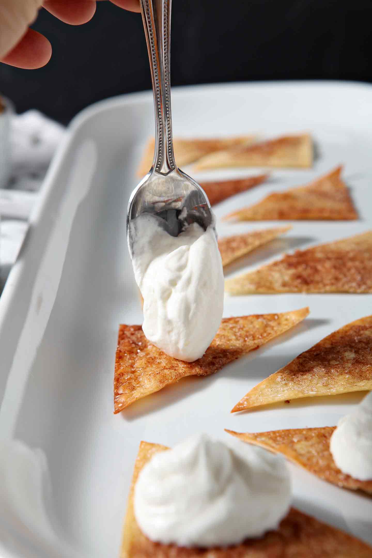 Sweetened whipped cream is dolloped onto Cinnamon-Sugar Wonton Chips to make the base for Halloween Dessert Nachos