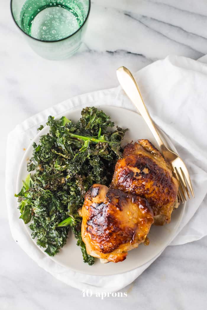 Honey Garlic Chicken Thighs served one a white plate with a side of Crispy Kale