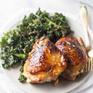 Different angle of Honey Garlic Chicken Thighs served one a white plate with a side of Crispy Kale