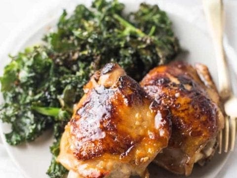 Different angle of Honey Garlic Chicken Thighs served one a white plate with a side of Crispy Kale
