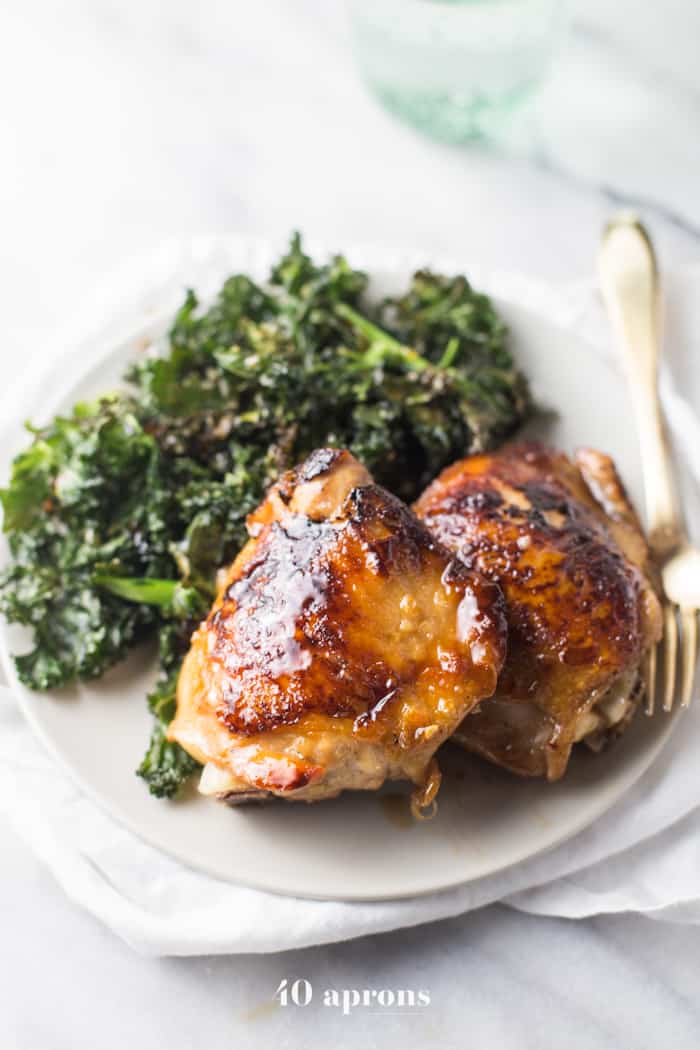 Different angle of Honey Garlic Chicken Thighs served one a white plate with a side of Crispy Kale