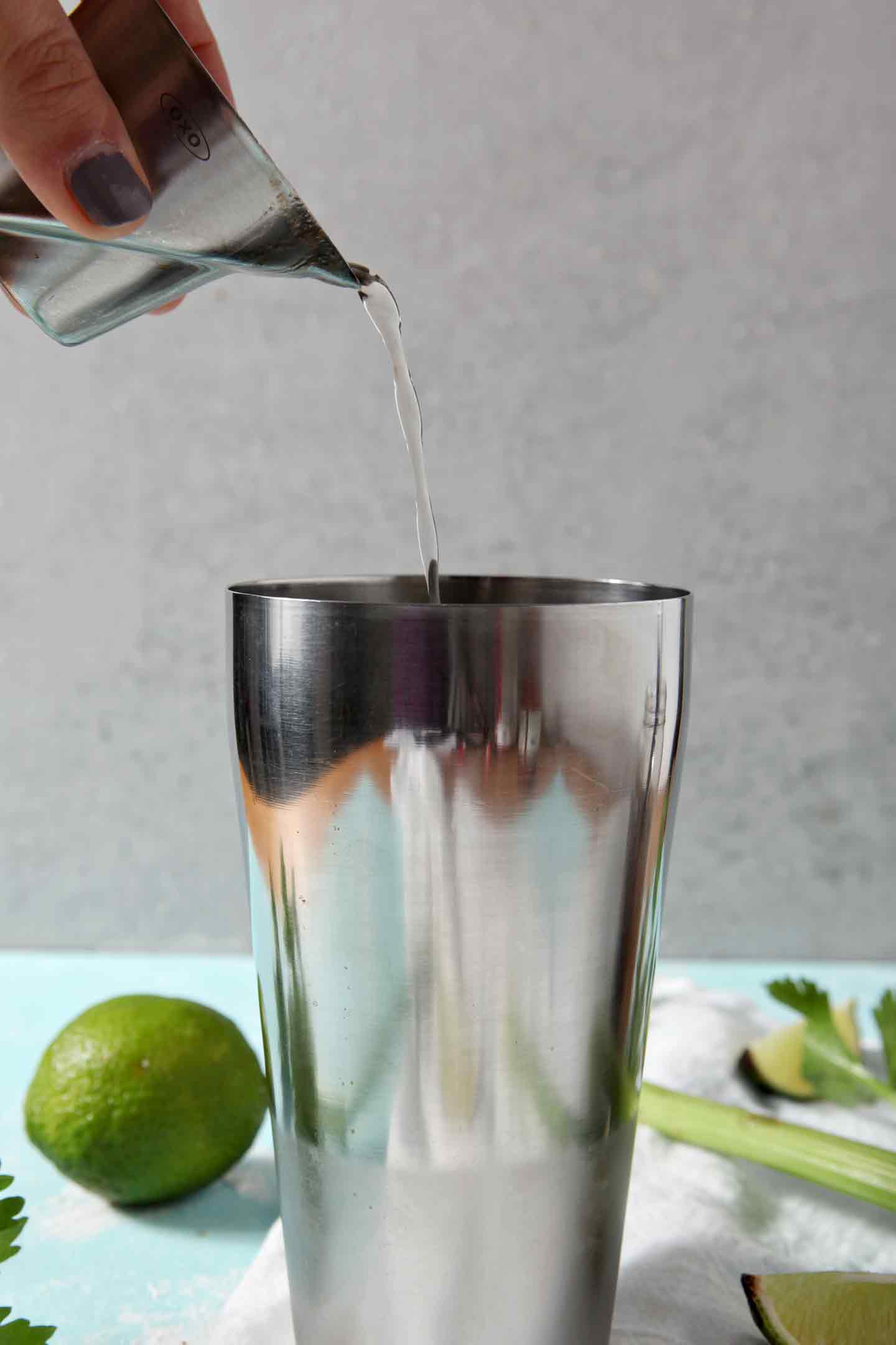 Vodka is poured into a cocktail shaker to make a BBQ Bloody Mary