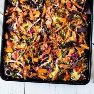 Horizontal image of Sheet Pan BBQ Chicken Nachos on a sheet pan, shown from above