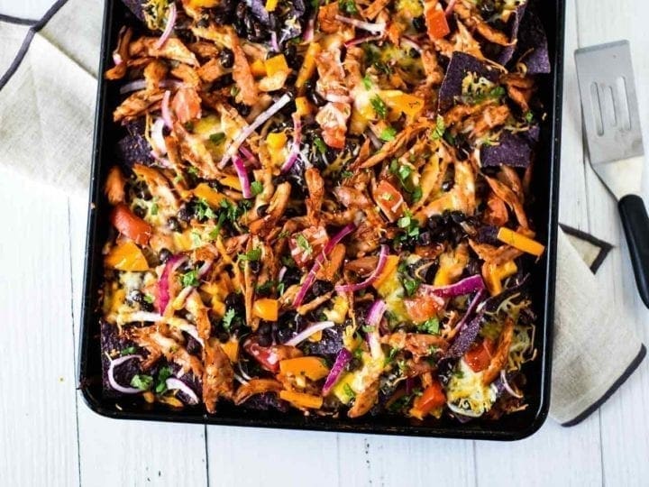 Horizontal image of Sheet Pan BBQ Chicken Nachos on a sheet pan, shown from above