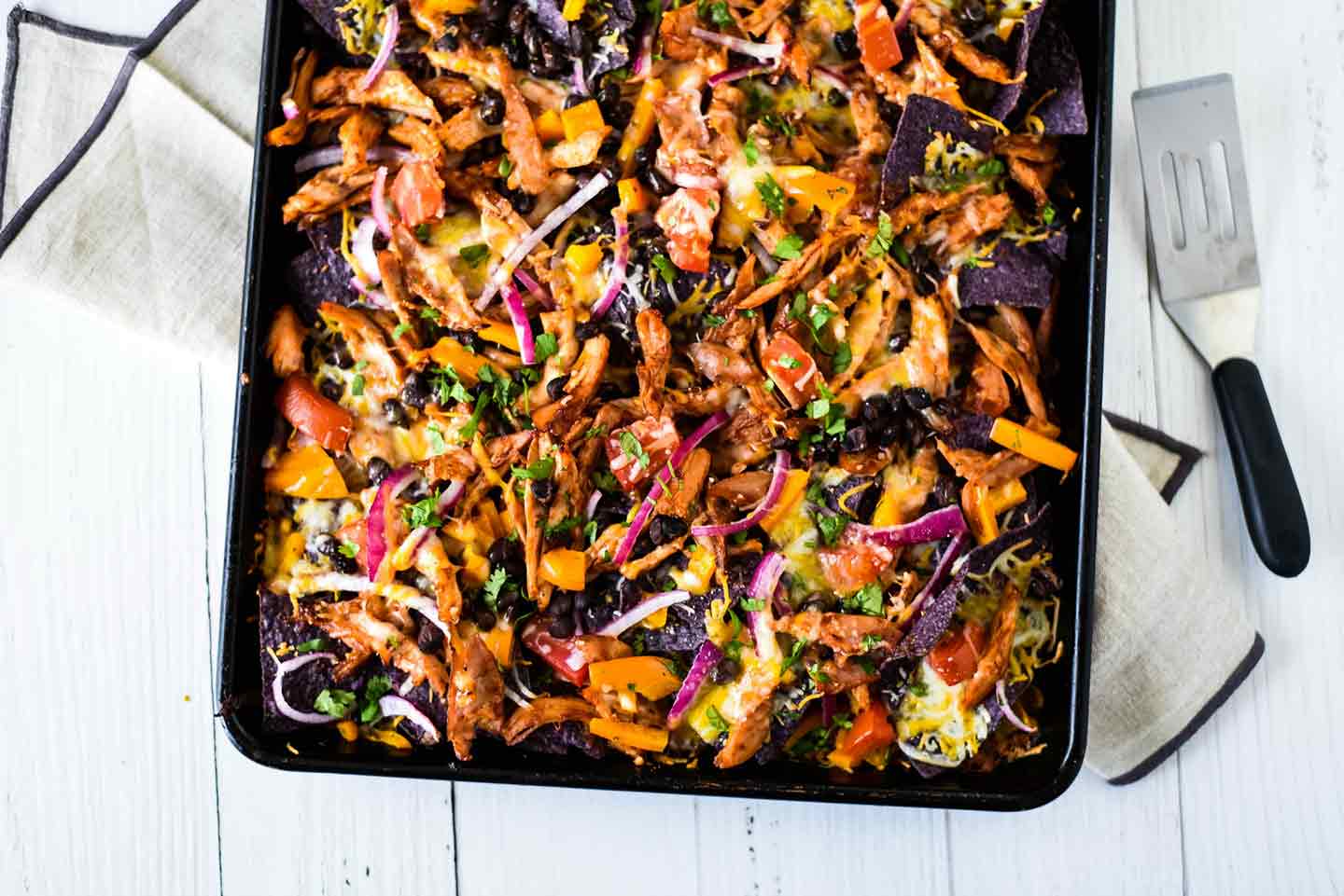 Horizontal image of Sheet Pan BBQ Chicken Nachos on a sheet pan, shown from above