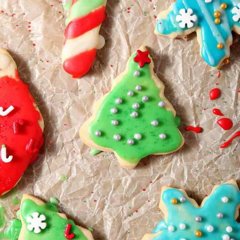 Decorated All-Butter Tea Cake Cookies are laid out on parchment paper to dry after icing and decorating