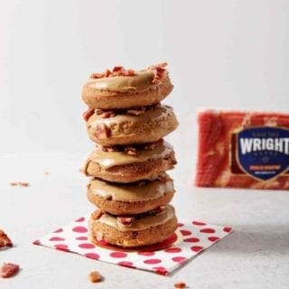 Baked Maple Bacon Donuts are stacked in front of a Wright Brand Bacon package