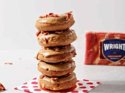 Baked Maple Bacon Donuts are stacked in front of a Wright Brand Bacon package