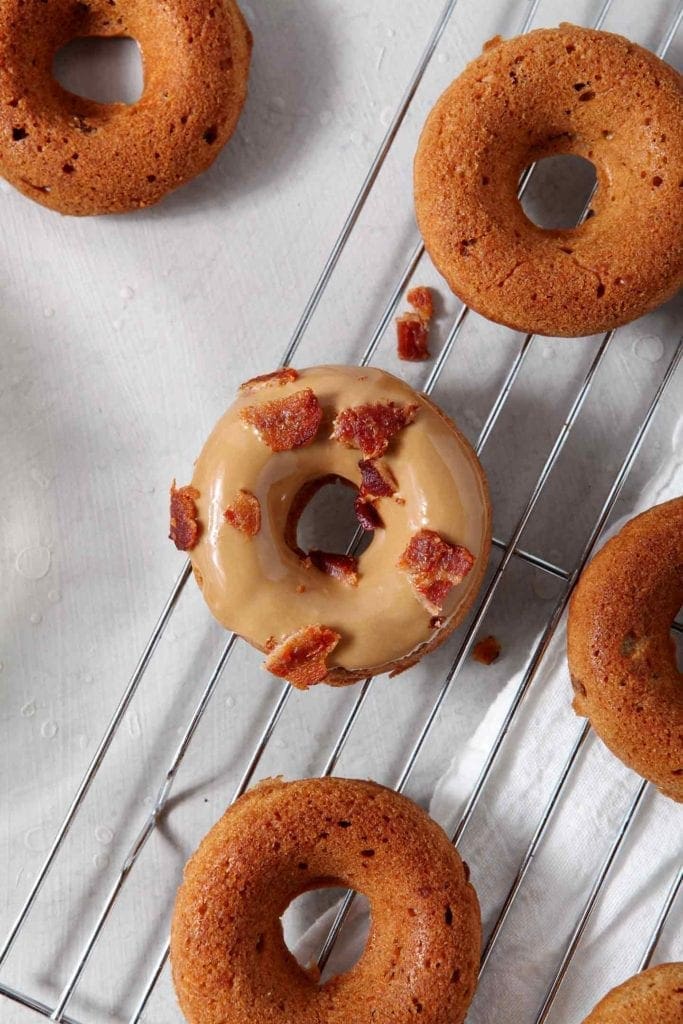 Baked Donuts on a wire cooling rack with a maple glaze and bacon crumbles