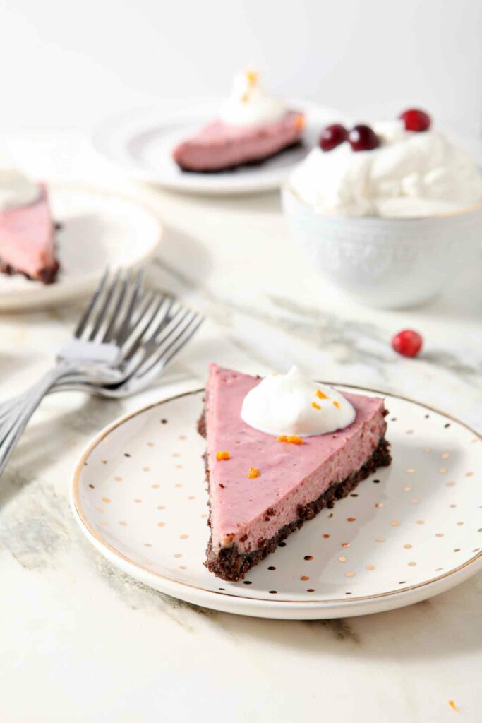 Slices of Creamy Cranberry Tart are served on gold and white plates with fresh whipped cream