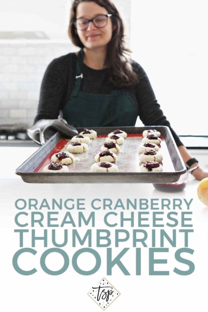 A woman holds a tray of thumbprint cookies toward the camera with Pinterest text