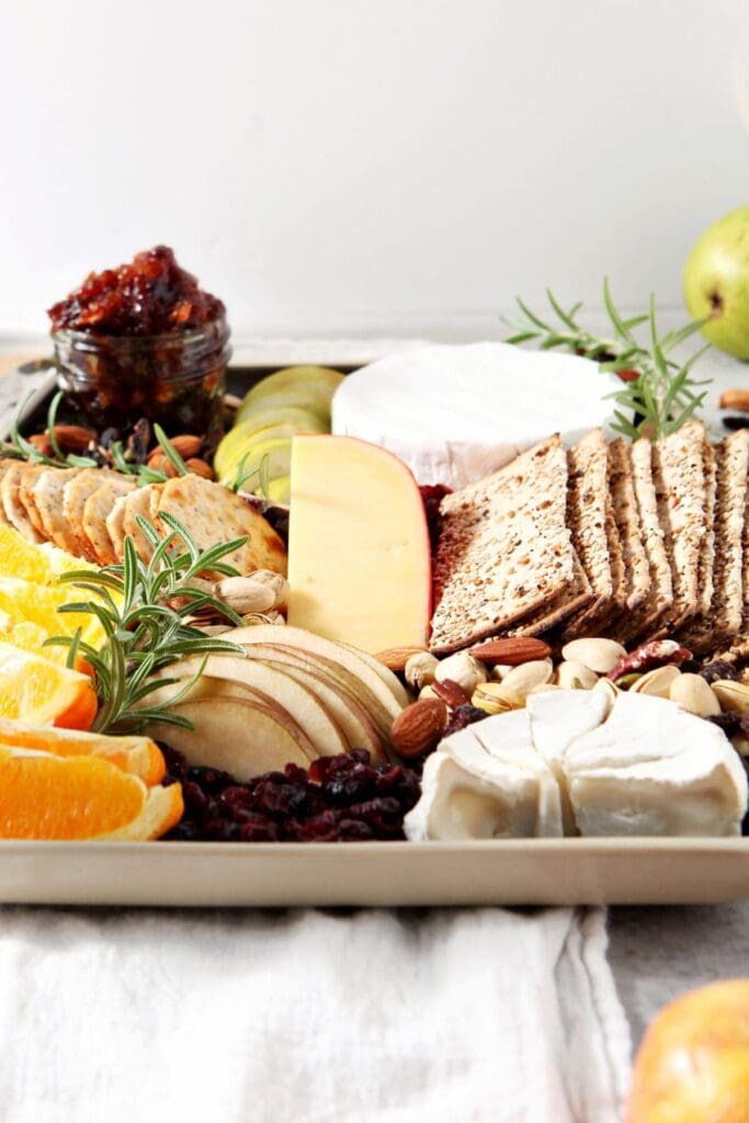 image of a cheese board for thanksgiving on a black and tan platter on a grey backdrop