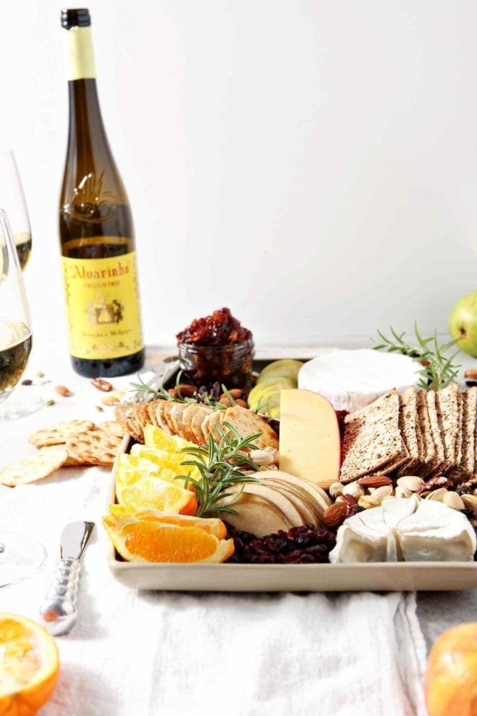 A Thanksgiving Cheese Board, served with Vinho Verde wine, sits on a grey background