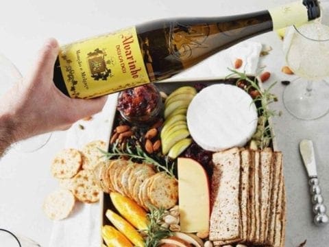 A person pours a glass of Vinho Verde wine over a Thanksgiving Cheese Board.
