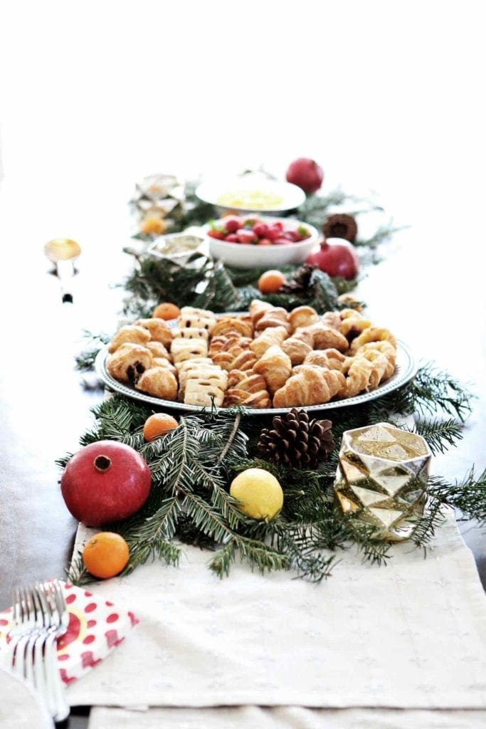 A holiday brunch table is set with pastries, fruit and scrambled eggs