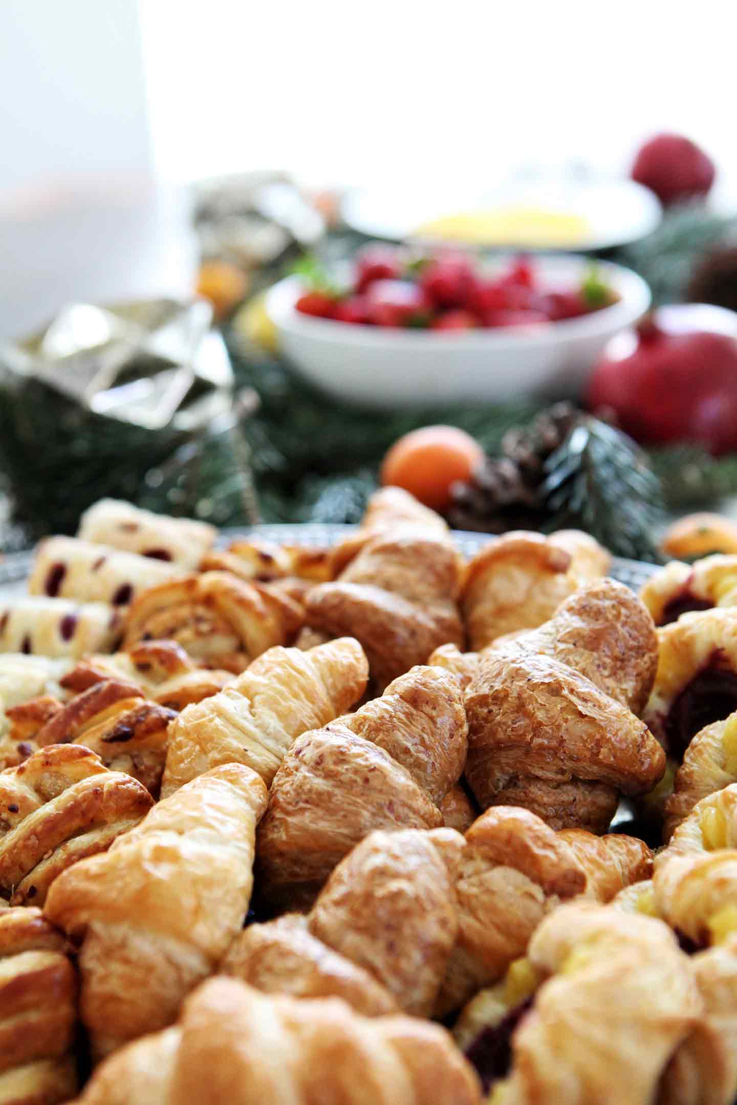 Pastries are shown on a silver platter with other holiday brunch dishes shown behind them