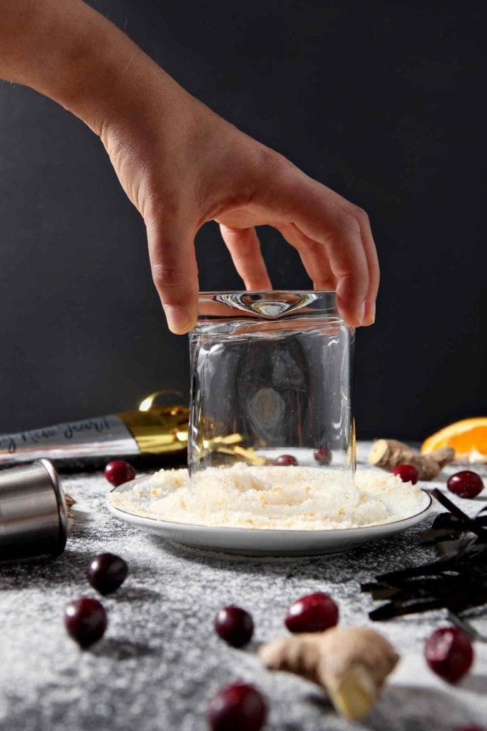 A glass is dipped into orange sugar before the drink is poured into it