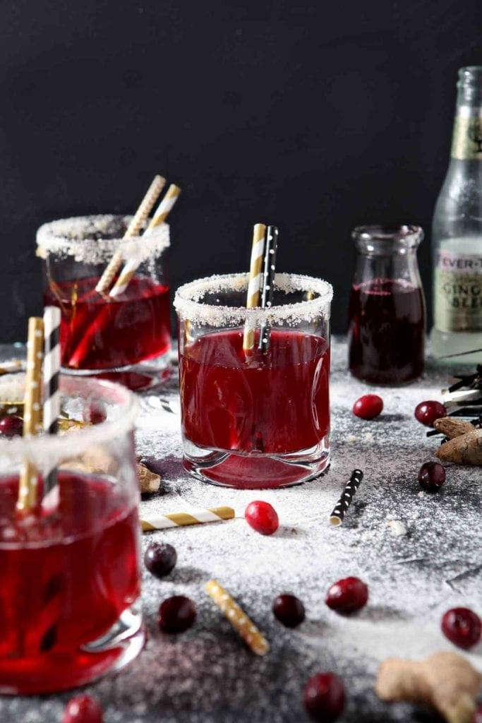 Three Sparkling Ginger Cranberry Mocktails are served on napkins with golden straws