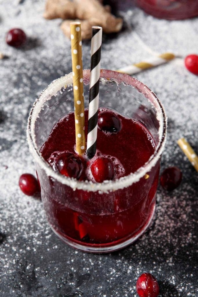 Close up of a Sparkling Ginger Cranberry Mocktail, surrounded by fresh cranberries