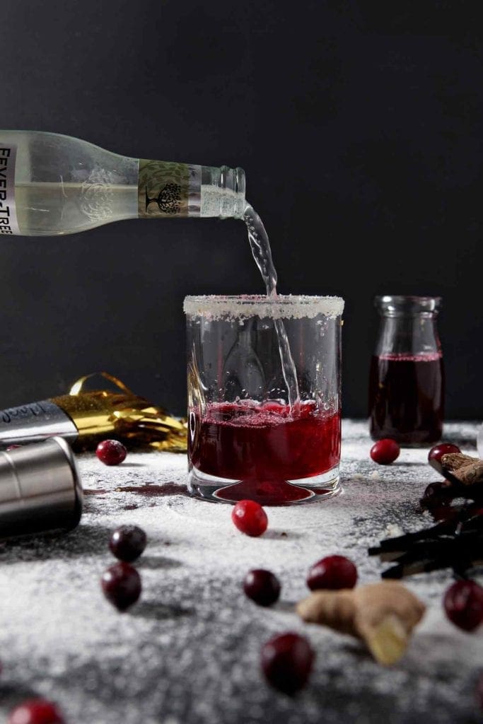 Ginger beer is poured into a glass to make a Sparkling Ginger Cranberry Mocktail