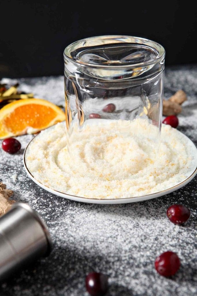 A glass is dipped into orange sugar before the drink is poured into it