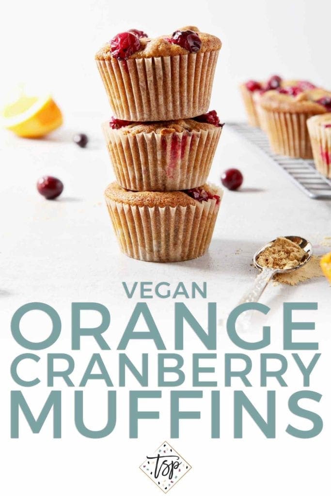 A stack of three Vegan Orange Cranberry Muffins stand beside a wire cooling rack with more muffins, shown with text