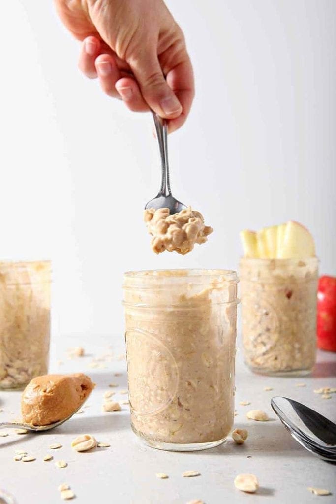 A spoonful of Peanut Butter Overnight Oats is lifted from a jar