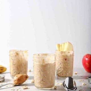 Three jars of Peanut Butter Overnight Oats are shown on a grey background with various toppings