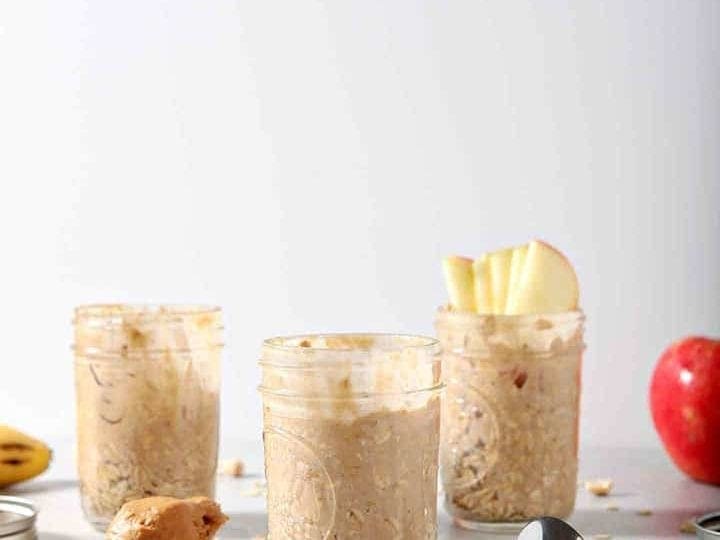 Three jars of Peanut Butter Overnight Oats are shown on a grey background with various toppings