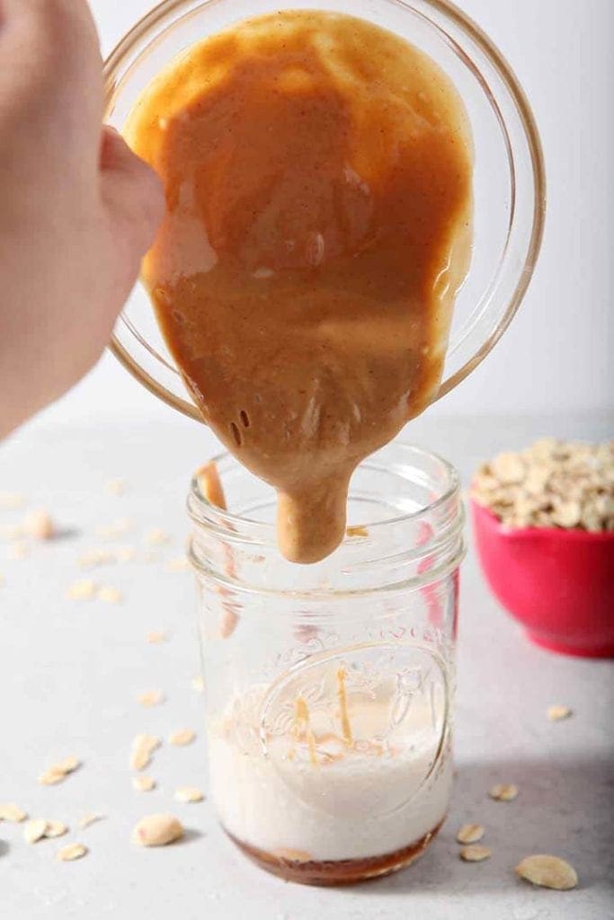 Peanut butter pours into a mason jar