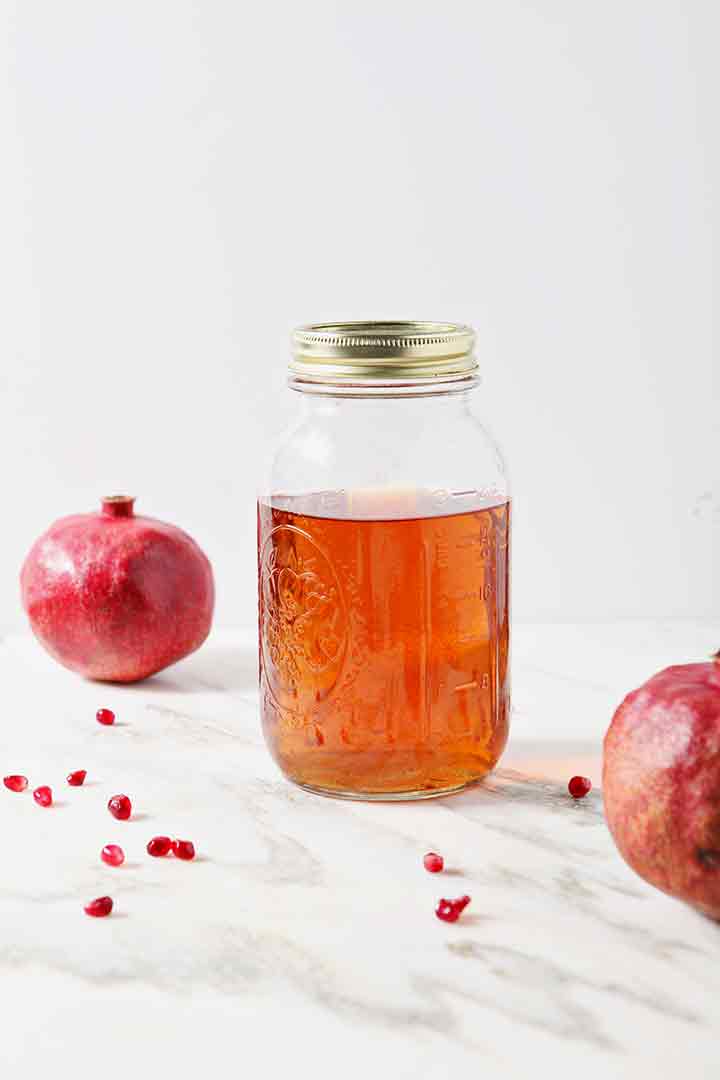 A jar holds Pomegranate-Infused Rum to make a Pomegranate Hot Buttered Rum