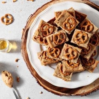 Boozy Bacon Pretzel Peanut Butter Bars are served on a round white plate