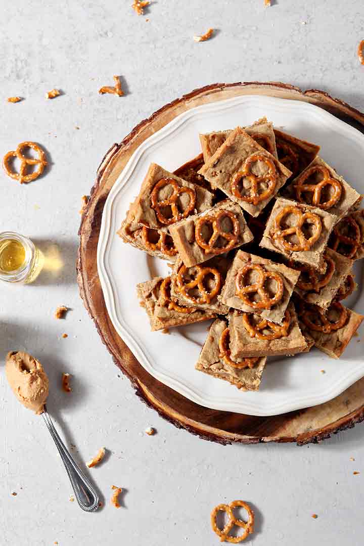 Boozy Bacon Pretzel Peanut Butter Bars are served on a round white plate