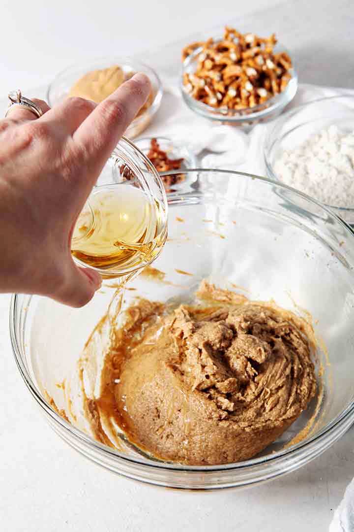 Bourbon is poured into the batter of Boozy Bacon Pretzel Peanut Butter Bars