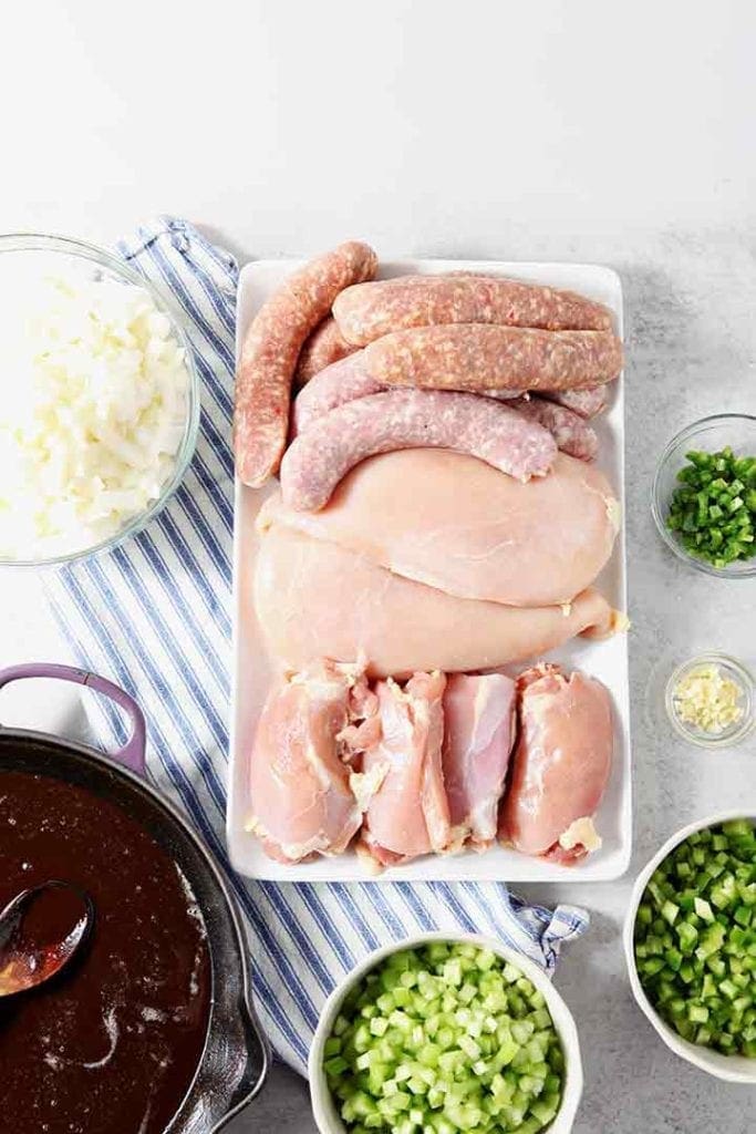 The meats for Chicken and Sausage Gumbo, along with the chopped veggies and roux, are shown on a light background