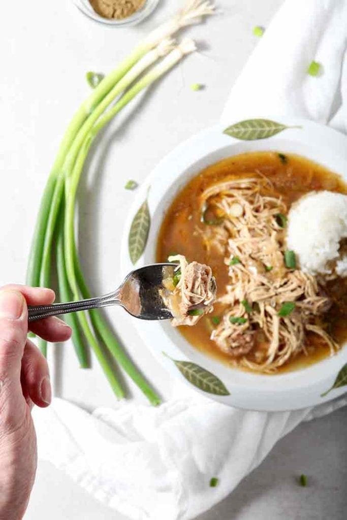 A man lifts a spoonful of Chicken and Sausage Gumbo out of the bowl