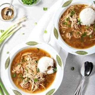 Two bowls of Chicken and Sausage Gumbo are served with rice and green onions