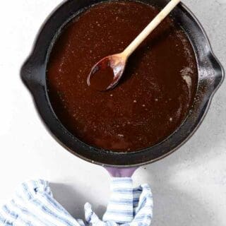 A dark roux is shown on a light background in a skillet