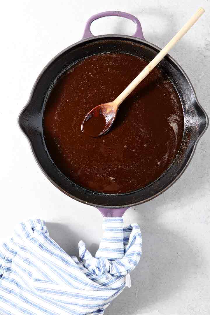 A dark roux is shown on a light background in a skillet