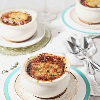 Three crocks holding Instant Pot French Onion Soup are served with red wine