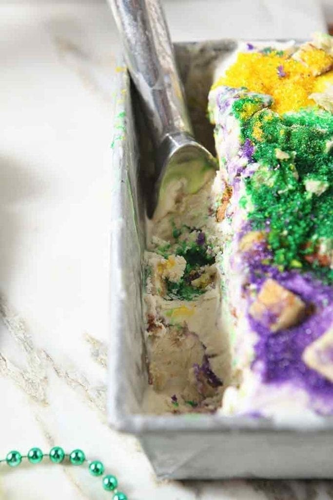 An ice cream scoop sits in a loaf pan of No Churn Mardi Gras King Cake Ice Cream