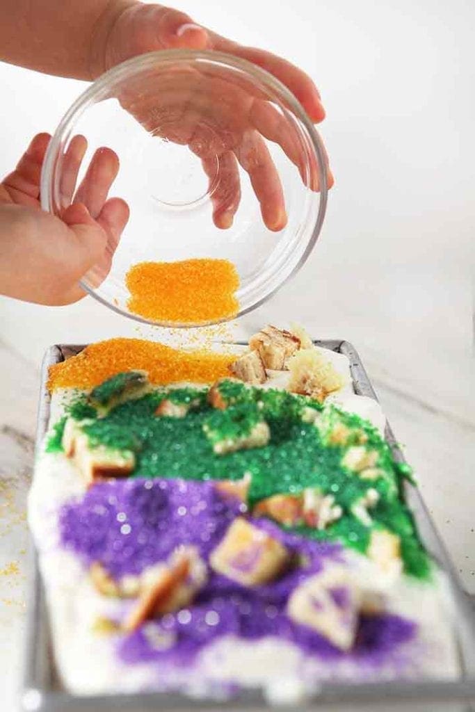 Gold sprinkles are spread on top of No Churn Mardi Gras King Cake Ice Cream before freezing