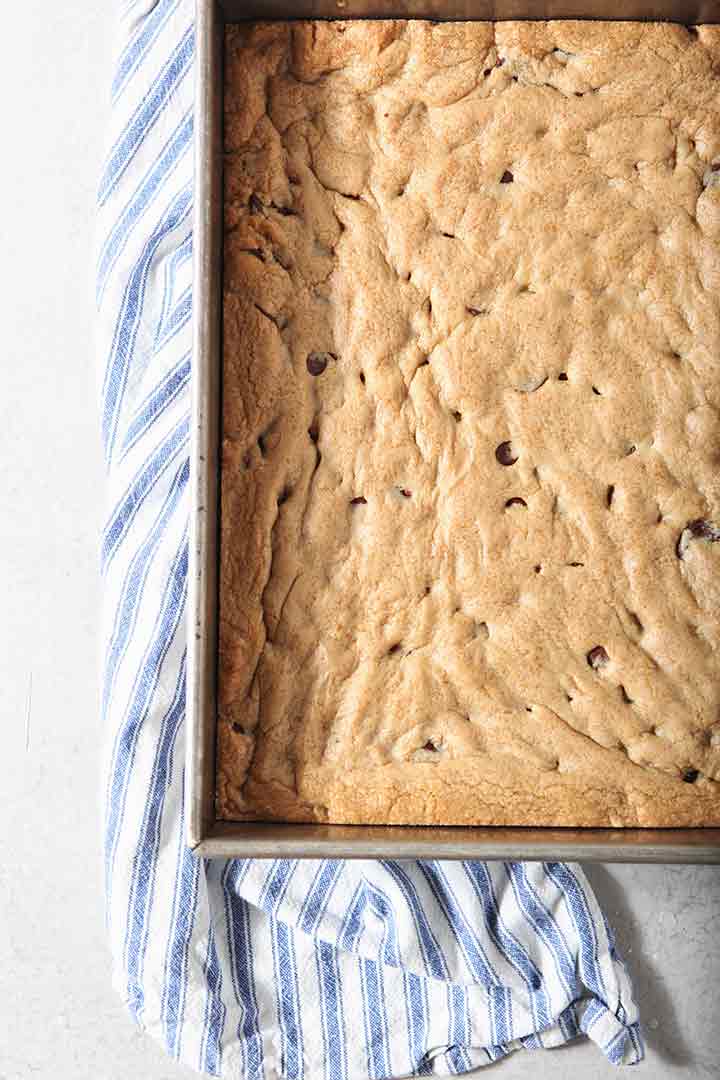 A pan of Chocolate Chip Cookie Bars cools on a countertop