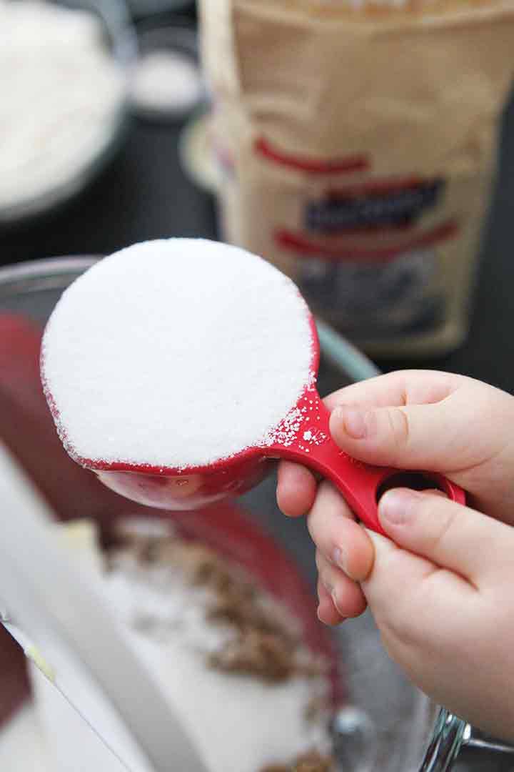 Sugar is poured into a mixing bowl to make the cookie batter