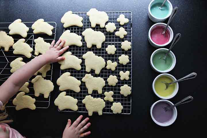 A girl touches lemon sugar cookies as they cool on wire racks