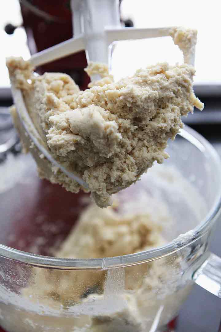 Cookie dough is shown on a dough beater in the stand mixer before going into the fridge for chilling