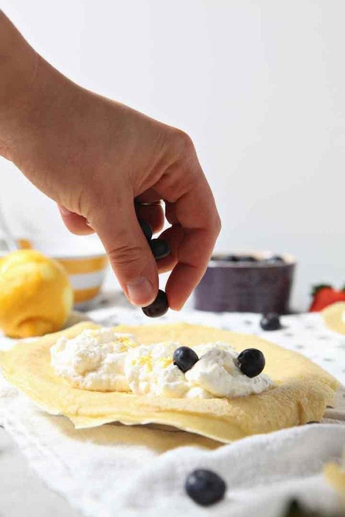 Blueberries are placed on top of lemon whipped cream to make a blueberry breakfast crepe