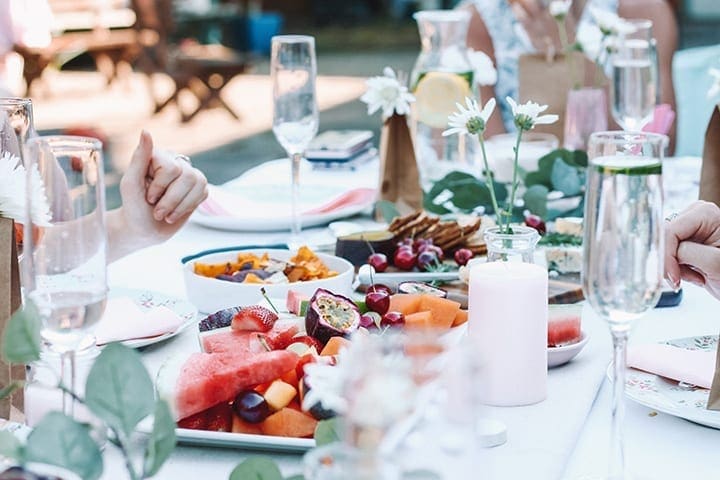 Women gather around a pink decorated table for homemade food and rose